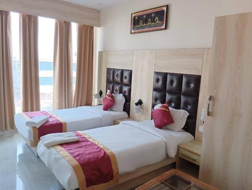 a hotel room with two beds and a window at Hotel SS Grand in Lucknow