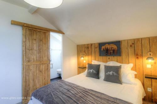a bedroom with a bed with a wooden wall at Casa di l'apa in Venaco