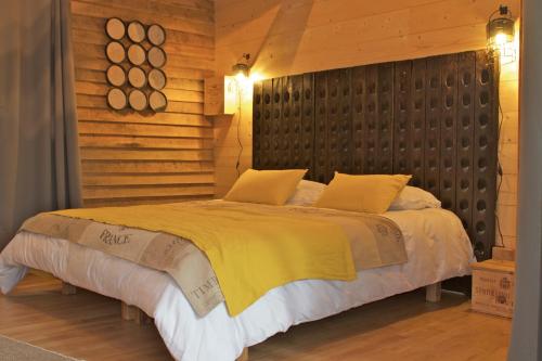 1 dormitorio con 1 cama grande y pared de madera en Ecolodges de Loire & Spa, en Gennes