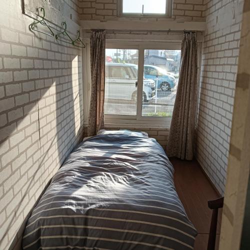 a bed in a small room with a window at Hakodate Guest House in Hakodate