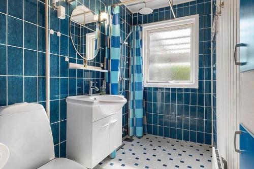 a blue tiled bathroom with a toilet and a sink at OH412-Hadsund-Halvrebene-94 in Hadsund