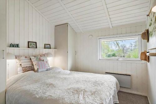 a white bedroom with a bed and a window at 3064-Stege-Maegleren-34 in Stege