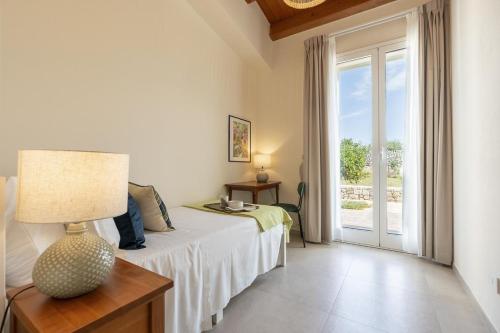 a bedroom with a bed with a lamp and a window at Villa Lumiere in Modica