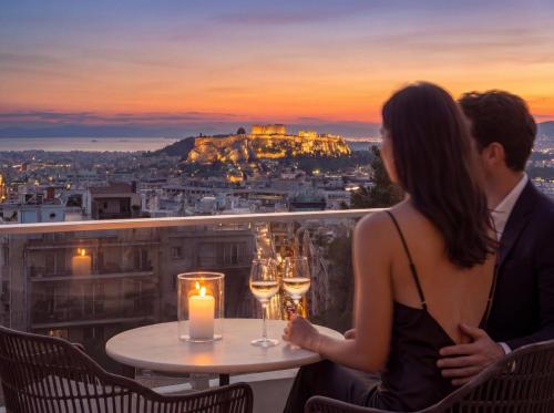 a man and a woman sitting at a table with wine glasses at St George Lycabettus Lifestyle Hotel in Athens