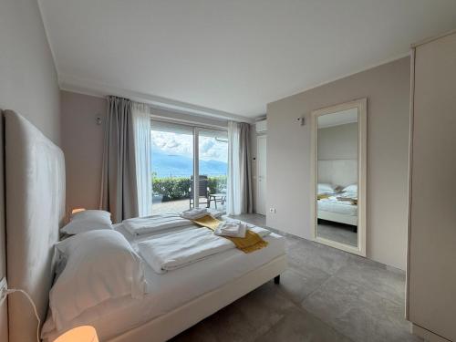 a bedroom with a bed and a large window at La Dolce Vita Relais - Hotel Gallo in Tignale