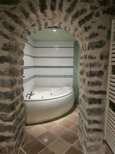a bath tub in a bathroom with a stone wall at La Ferme du Mont in Foissy