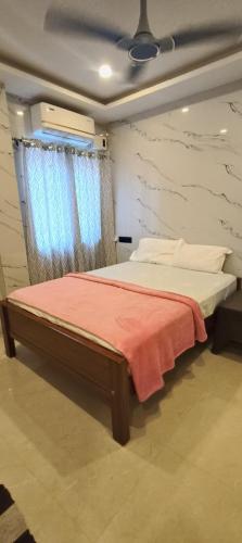 a bedroom with a bed with a red blanket and a window at RVS Residency in Kāyalpattinam
