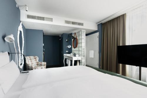 a bedroom with a white bed and a blue wall at Grand Ferdinand Vienna – Your Hotel In The City Center in Vienna