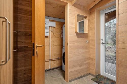 a small bathroom with wooden walls and a door at 2314-Stege-Ulvshale-Cedervej-4-B in Tyrholm