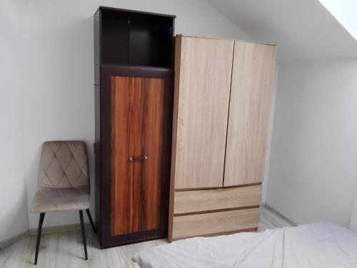a bedroom with a wooden cabinet and a chair at Pod Lasem in Altanka