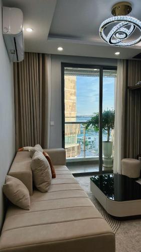a living room with a couch and a large window at Ruby's Home The Ruby Hạ Long in Ha Long