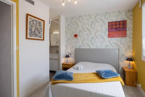 a bedroom with a bed with two blue pillows on it at Le Cyclamens - MC et JC in Onet le Château