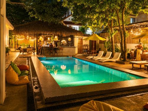 a swimming pool with chairs and a table and a restaurant at THE PLACE Hostel Phnom Penh in Phnom Penh