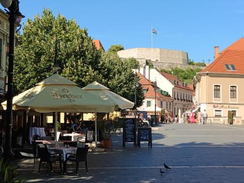 a street with tables and chairs under an umbrella at Céhmesterek apartman in Eger