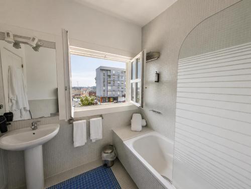 a bathroom with a tub and a sink and a window at Las Carolinas Garden in Santander
