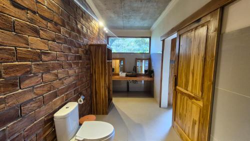 a bathroom with a brick wall and a toilet at Green Haven Homestay in Tetebatu