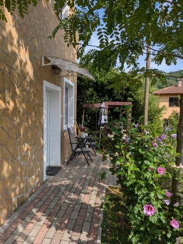 a patio with a table and an umbrella and some flowers at Szőlőskert Vendégház in Baj