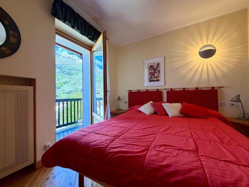a red bed in a bedroom with a large window at Borealis - VOTRE MAISON in Cogne