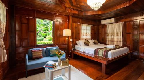 a bedroom with a bed and a couch and a window at Wellness Resort Rayong Managed by the SCN in Ban Huai Pla Kang
