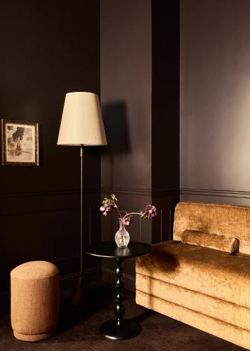 a living room with a table with a lamp and a couch at L'Opale Noire in Paris
