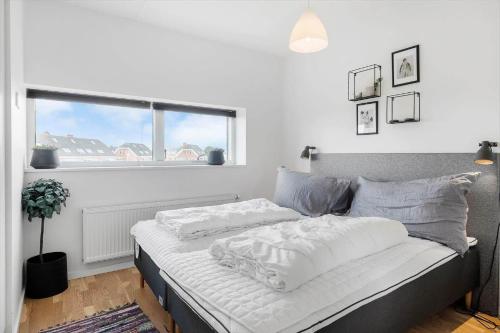 a bedroom with a bed with white sheets and a window at 0385-Romo-Hollaenderstraedet-42 in Høm