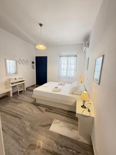 a white bedroom with a bed and a desk at Kionia Galini Bangalows in Kionia