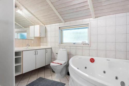 a bathroom with a tub and a toilet and a sink at 0046-Romo-Trinnesvej-17 in Høm