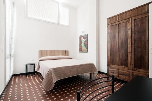 a bedroom with a bed and a wooden cabinet at Appartamento Letterario e Musicale - Art & Design in Grosseto