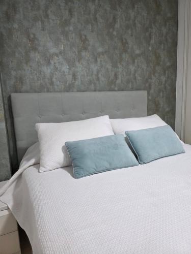 a white bed with two blue pillows on it at Apartamento Acapulco III Primera linea in Oropesa del Mar