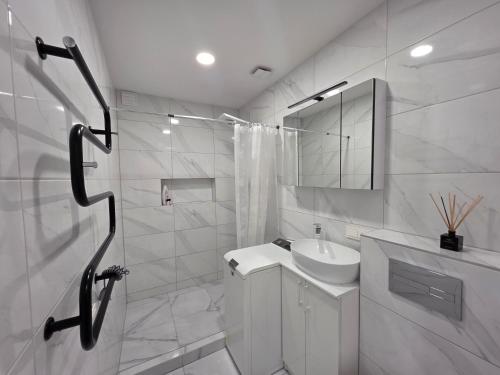 a white bathroom with a sink and a shower at Nemunas Riverside in Kaunas