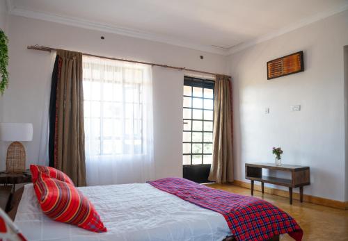 a bedroom with a bed and a table and windows at Miti Retreat Nanyuki in Naro Moru