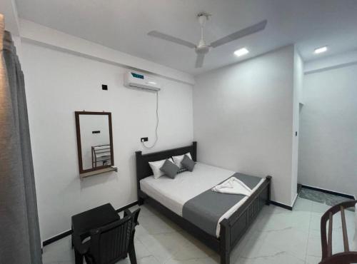 a bedroom with a bed and a mirror and a chair at NRT Beach Hotel in Trincomalee