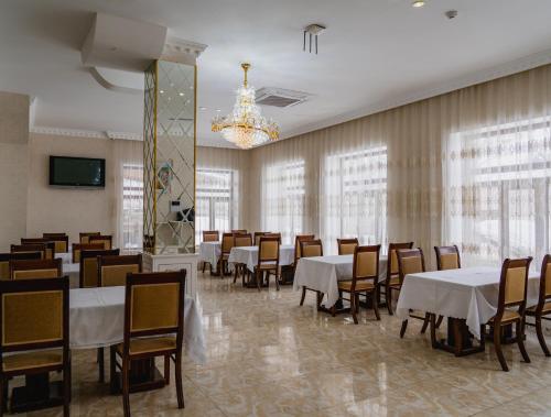 a dining room with tables and chairs and a chandelier at WhiteHotelGabala in Gabala