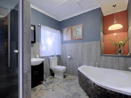 a bathroom with a tub and a toilet and a sink at Raptor's Rest Bed and Breakfast in Empangeni