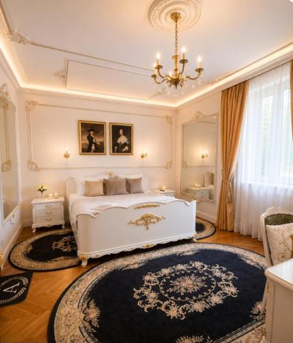 a bedroom with a white bed and a chandelier at Queen's Astoria Design Hotel in Belgrade