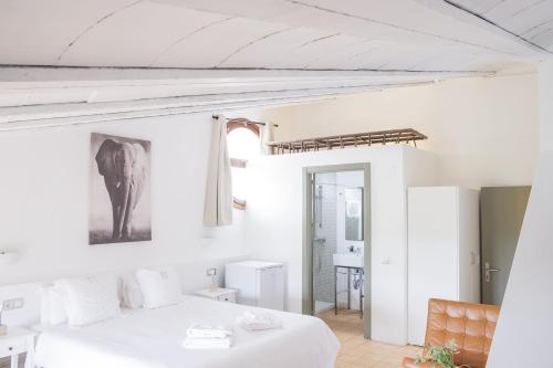 a white bedroom with a bed and a mirror at Mas del Mar in Sant Pere Pescador