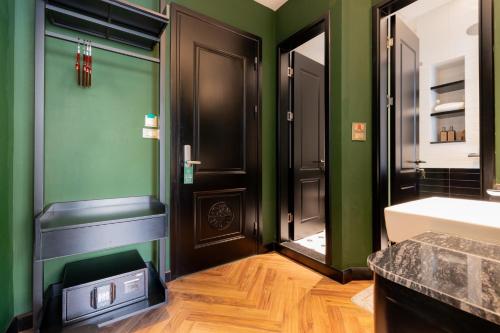 a bathroom with green walls and a sink and a mirror at Brilliant Jade Suites in Hanoi