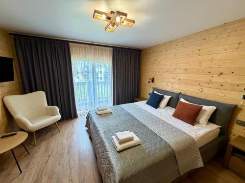 a bedroom with a bed and a chair and a window at Chokolate house in Bukovel