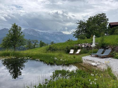 two chairs and an umbrella next to a pond at Hörndlhof in Abtenau