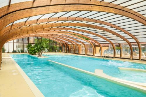 a large swimming pool with a wooden ceiling at Résidence Pierre & Vacances Les Cottages Du Lac in Parentis-en-Born