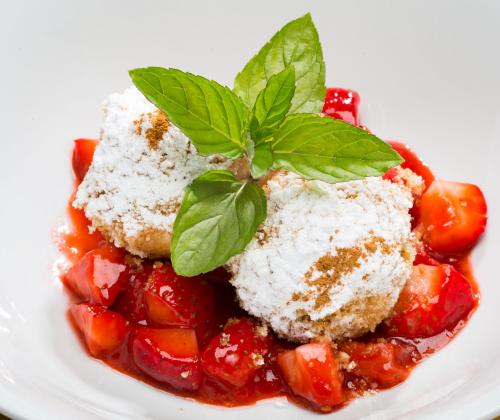 a plate of food with strawberries and powdered sugar at Der Erlhof Restaurant & Landhotel in Zell am See