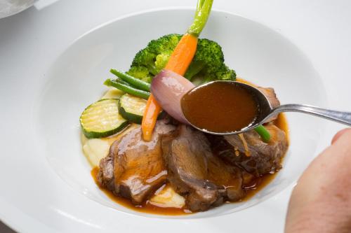 a plate of food with meat and vegetables with a spoon at Der Erlhof Restaurant & Landhotel in Zell am See