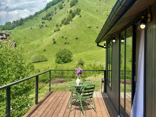 a balcony with a table with a vase of flowers at Uno Cottage Kazbegi in Kazbegi