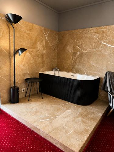 a bathroom with a bath tub and a table at Nowad Hotel in Giurgiu