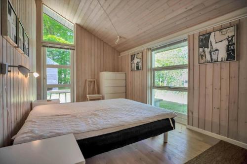 a bedroom with a large bed and two windows at 11806-Nykobing-Sj-Klintegarden-1 in Klint