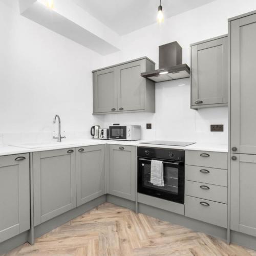 a kitchen with white cabinets and a stove top oven at Modern 3 Bed Townhouse - Wolverhampton Centre - Gated Development - Bedroom TV 1CO in Wolverhampton