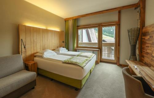 a bedroom with a bed and a chair and a window at Termag Hotel Jahorina in Jahorina