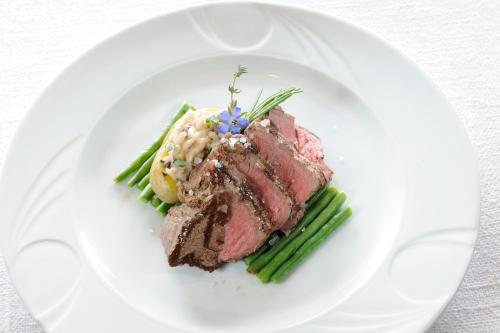 a white plate with a piece of meat and asparagus at Naturhotel Alpenrose in Millstatt