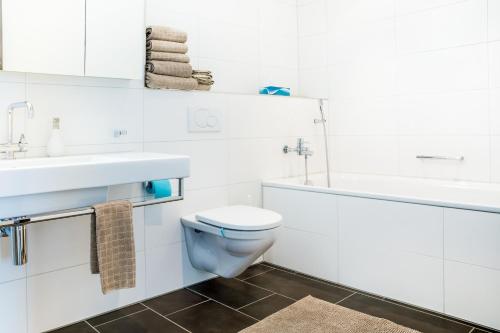 a white bathroom with a toilet and a sink at White Apartment in Andermatt