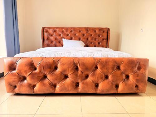 a brown tufted bed in a bedroom at Volcanoes Stay Musanze in Kigali